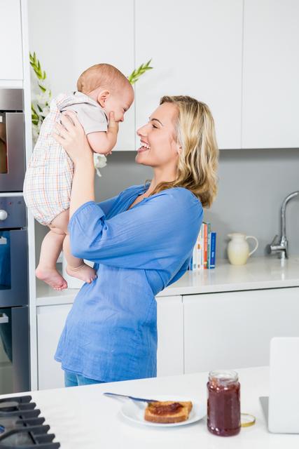 Happy Mother Holding Baby Boy in Modern Kitchen - Download Free Stock Photos Pikwizard.com