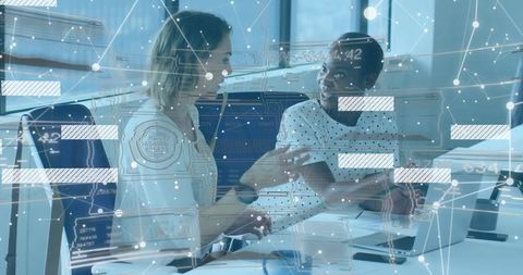 Businesswomen collaborating over data visualization on laptop in office with network overlay