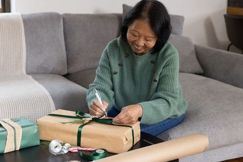 Senior Woman Joyfully Wrapping Gifts for Holiday Celebration