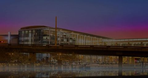 Glass-fronted modern building and elevated highway reflecting city lights at twilight