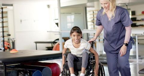 Pediatric therapist guiding child in wheelchair during mobility rehabilitation session