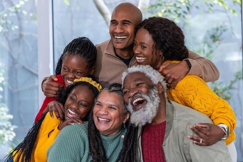Multigenerational black family laughing and embracing during cozy home reunion