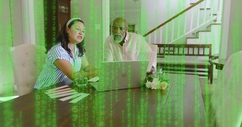 Couple reviewing documents on laptop at home with digital code overlay for cybersecurity