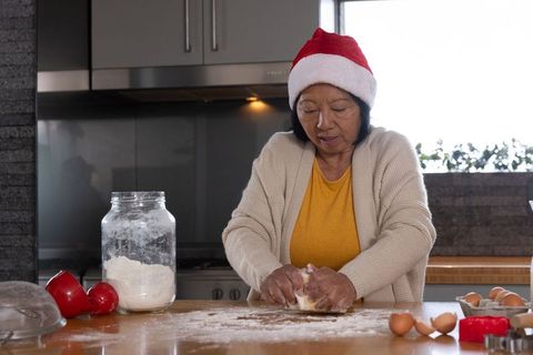 Senior Woman Baking Indoors Wearing Festive Santa Hat