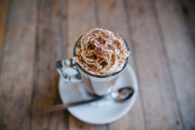 Whipped cream coffee cup on a wooden table, perfect for cafes, menus, and cooking blogs. Suitable for promoting cozy cafe environments and hot beverages, as well as displaying quality barista craftsmanship.