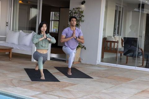Diverse individuals practicing yoga by poolside terrace in harmony