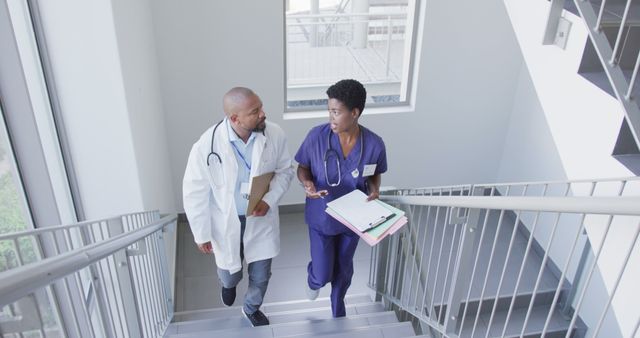 African american male and female doctors holding clipboard and talking at hospital. Medicine, healthcare, lifestyle and hospital concept.