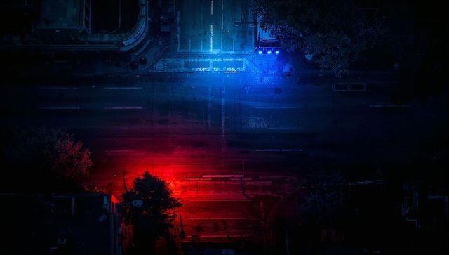 Aerial night street glowing with red and blue emergency lights, neon urban drone view