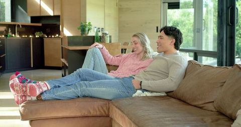 Couple relaxing on sofa in cozy open-plan living room with natural light and knit tops