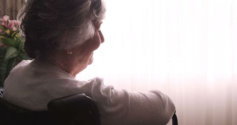 Senior Woman in Wheelchair Enjoying Sunlight at Home