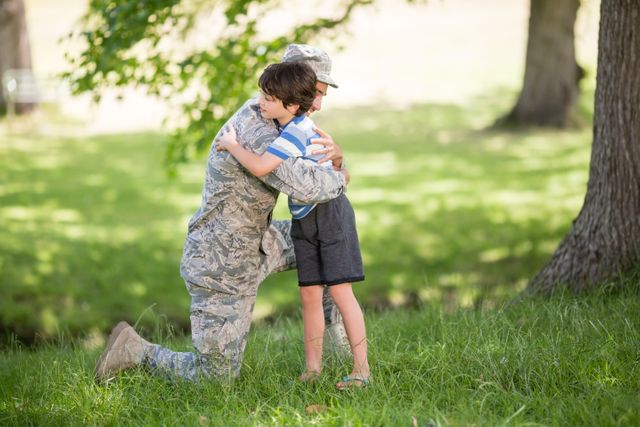 Army soldier embracing boy in park on a sunny day