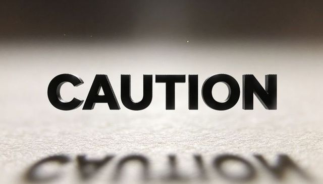 Floating bold caution lettering casting blurred reflection on paper with soft lighting