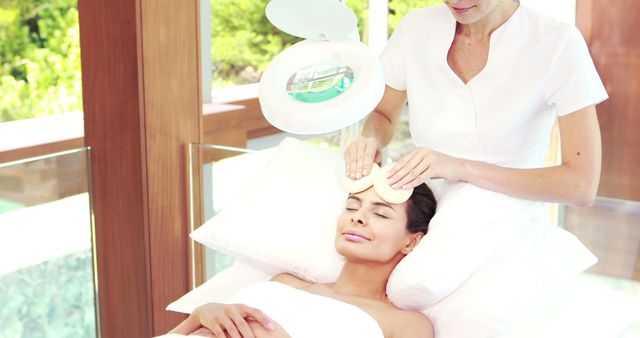 Spa therapist giving a calming facial treatment to a client in a serene, luxurious environment. This could be used for promoting wellness and spa services, skincare products, or luxury retreats, emphasizing relaxation, beauty, and professional care.