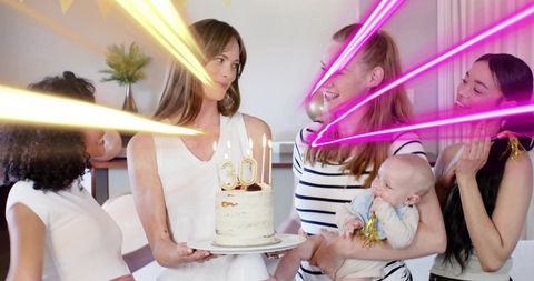 Holding 30th birthday cake while friends and family celebrate at home