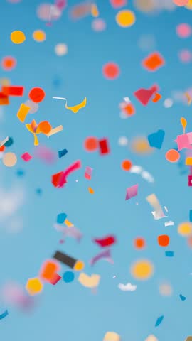 Vertical celebration loop of colorful confetti and streamers drifting across blue sky
