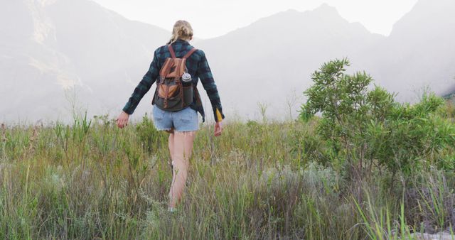 Female Hiker Walking Through Grass Field with Mountain View - Download Free Stock Images Pikwizard.com