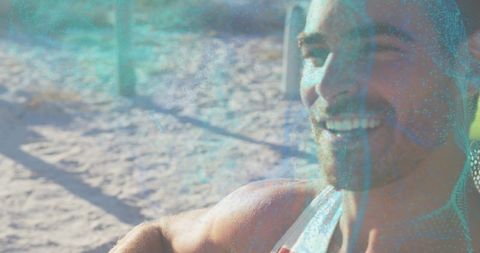 Smiling bearded man posing in tank top on sunlit beach with turquoise tint and copy space