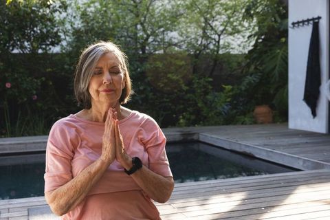 Senior woman meditating peacefully by garden pool
