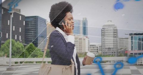 Professional Woman Walking in Urban Setting Holding Phone and Coffee
