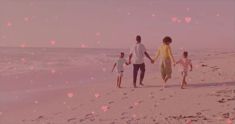 African american family walking hand in hand on sunrise beach with heart bokeh