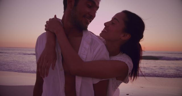 This image shows a romantic scene where a biracial couple is embracing and laughing on a beach at sunset. The mood is joyful and intimate, showcasing a strong sense of love and connection between them. This photo could be used for promoting travel destinations, honeymoon packages, relationship advice articles, or advertisements for dating services. It’s also ideal for social media posts about love, connection, and spontaneous moments.