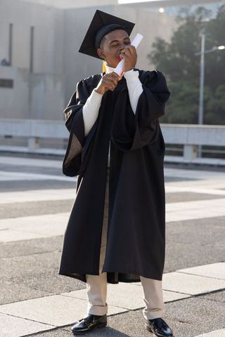 Joyful african american graduate embracing diploma on campus plaza