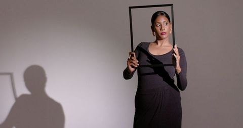 Artistic asian indian woman holding frame with shadow on wall