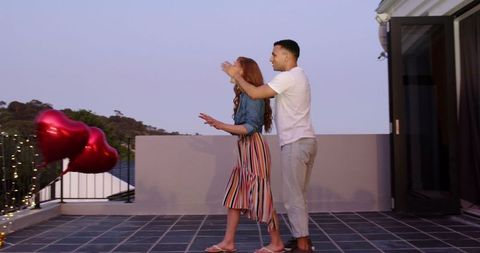 Romantic Rooftop Proposal with Heart Balloons During Sunset