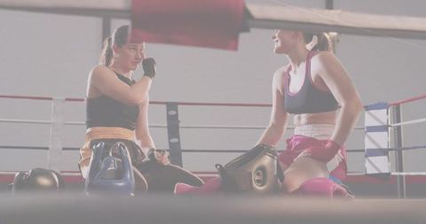 Female Boxers Resting in Ring After Training Session Showing Teamwork and Fitness Focus