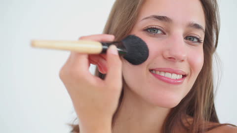Smiling Woman Applying Makeup with Brush to Face