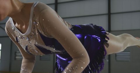 Teenage gymnast performing with purple leotard and ball