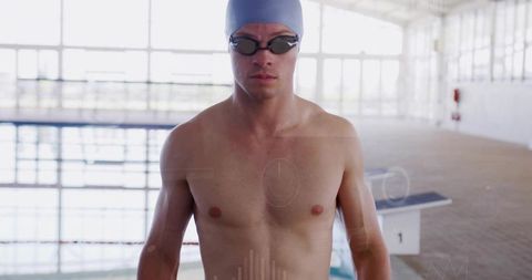 Male competitive swimmer standing on pool deck wearing cap and goggles preparing to race