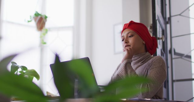 Thoughtful Woman with Red Headwrap Working on Laptop at Home - Download Free Stock Images Pikwizard.com