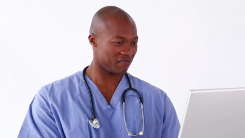 Smiling Doctor Using Laptop with Stethoscope Around Neck