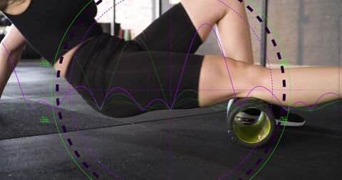 Female athlete rolling thigh with foam roller for muscle recovery and mobility