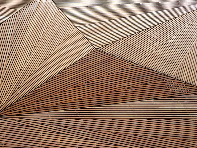Geometric wooden wall featuring intricate diagonal patterns creating a striking and modern design. This textured background can be used in interior design projects, architectural presentations, or as a backdrop in advertisements to convey an artistic and contemporary feel. Ideal for illustrating craftsmanship and design creativity in both print and digital media.