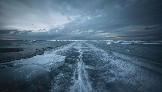 Moody arctic seascape with central slushy ice channel and broken ice floes at horizon