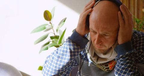 Focused Man Enjoying Music at Home with Headphones in Natural Light
