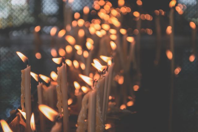 Rows of burning candles creating a serene and spiritual atmosphere. Ideal for illustrating concepts of meditation, prayer, tranquility, and solemn rituals. Can be used for religious context, relaxation and wellness materials, or ambiance themes.