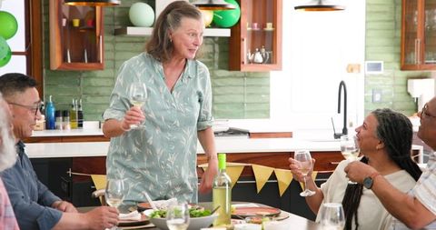 Senior Friends Toasting at Dinner Party in Modern Kitchen