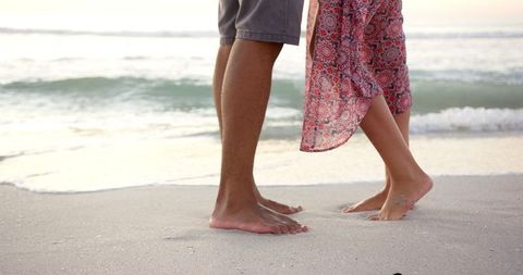 Romantic Beach Sunset with Barefoot Couple Standing by Ocean