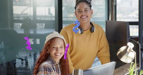Young colleagues smiling and collaborating in modern open-plan office with headphones