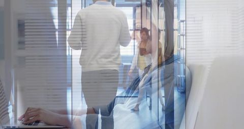 Typing worker in glass corridor with laptop tablet smartphone reflecting office teamwork