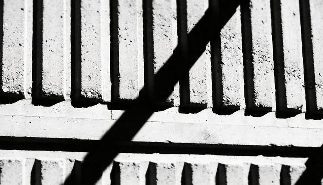 Diagonal Shadow Crossing Grooved Concrete Facade with Vertical Ribs and Ledges