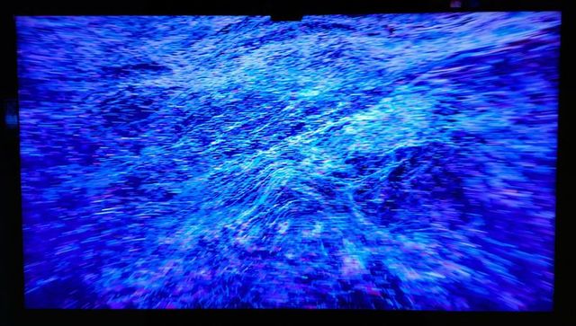 Luminous blue particle wave display on thin-bezel screen - futuristic abstract digital energy