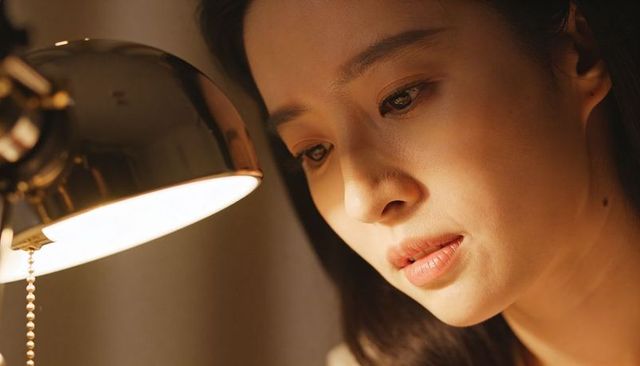Gazing asian woman bathing in warm lamp light, intimate closeup conveying contemplation