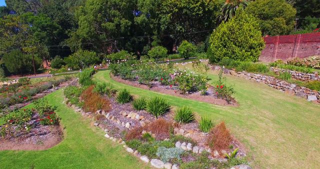 Image showcases a lush garden with well-maintained stone pathways and vibrant flowerbeds. Ideal for use in landscaping, gardening blogs, nature magazines, and outdoor design promotions.