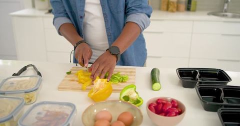 African american man slicing bell peppers for healthy meal prep in modern kitchen