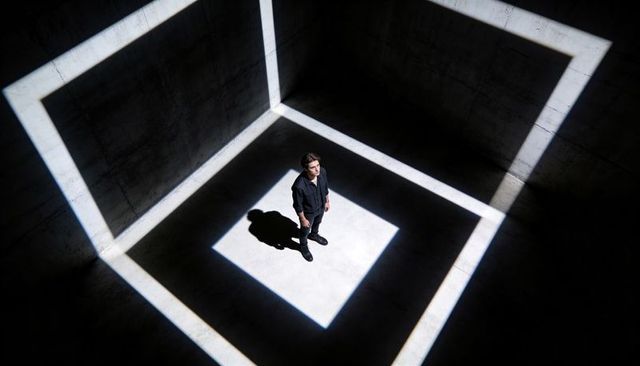 Man Standing in Geometric Light Squares on Concrete Floor Overhead Minimalist Scene