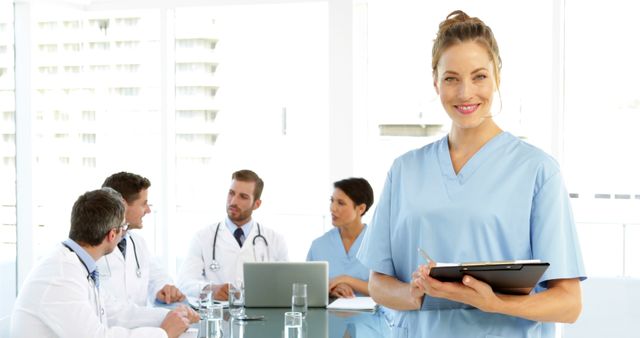 Confident female nurse with medical team discussion in background - Download Free Stock Images Pikwizard.com